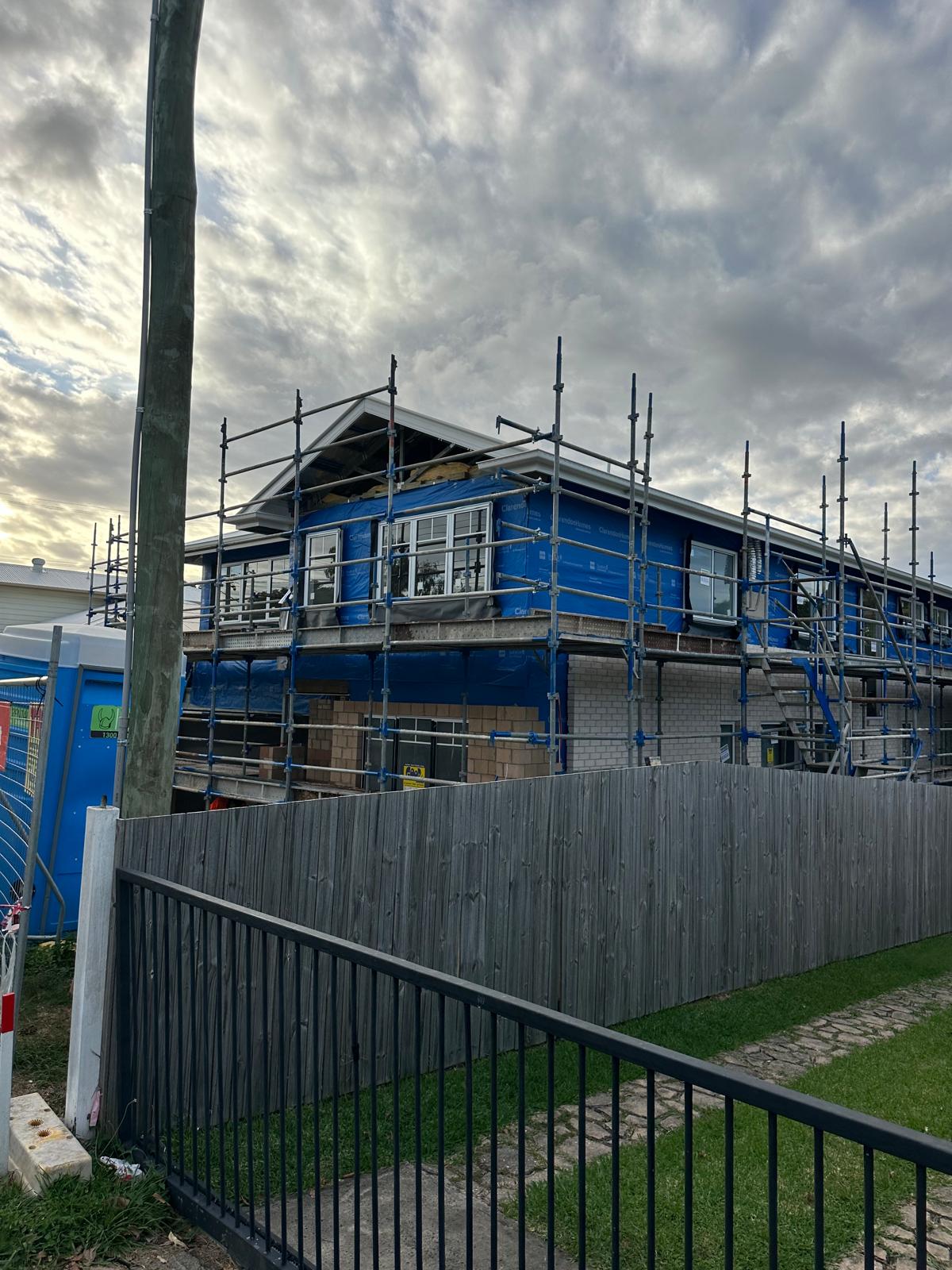 Street view of scaffold surrounding a two-storey home